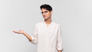 Genç yakışıklı adam kendini mutlu hissediyor ve gülümsüyor. Yanında duran bir nesneye ya da konsepte bakıyor.