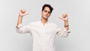 Genç yakışıklı adam gururlu, kibirli ve kendinden emin, tatmin olmuş ve başarılı görünüyor, kendini işaret ediyor.