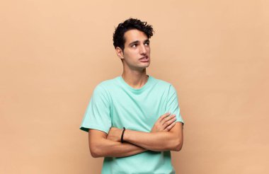 Genç yakışıklı adam şüphe ediyor ya da düşünüyor, dudağını ısırıyor ve kendini güvensiz ve gergin hissediyor, kenarda yer arıyor.