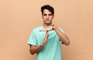 Genç yakışıklı adam ciddi, sert, kızgın ve canı sıkkın görünüyor.