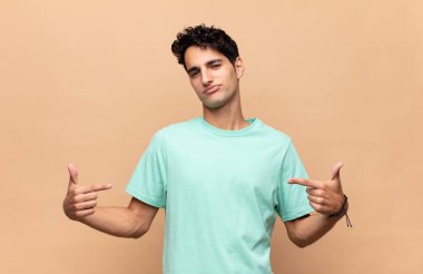 Genç yakışıklı adam gururlu, kibirli, mutlu, şaşırmış ve tatmin olmuş görünüyor, kendini gösteriyor, kazanan gibi hissediyor.