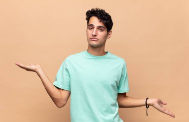 Şaşkın, şaşkın ve stresli görünen genç bir adam. Farklı seçenekler arasında merak ediyor. Belirsiz hissediyor.