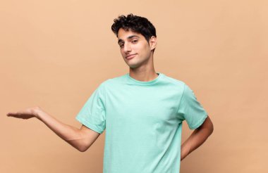 Genç yakışıklı adam gülümsüyor, kendinden emin, başarılı ve mutlu hissediyor, fotokopi alanında fikir veya konsept gösteriyor.