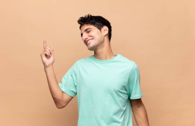 Genç yakışıklı adam gülümsüyor, kaygısız hissediyor, rahat ve mutlu, dans ediyor ve müzik dinliyor, bir partide eğleniyor.