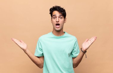 Genç yakışıklı adam mutlu, heyecanlı, şaşırmış ya da şok olmuş hissediyor, gülümsüyor ve hayrete düşüyor.