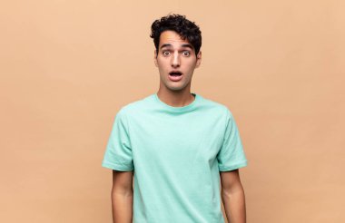 Genç ve yakışıklı bir adam şok olmuş ya da şaşırmış görünüyor, ağzı açık bir şekilde 