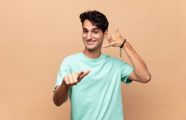 Genç yakışıklı adam neşeyle gülümsüyor ve kamerayı işaret ediyor. Sonra seni arıyor, telefonla konuşuyor.