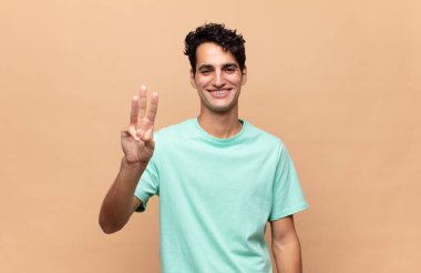 Genç yakışıklı adam gülümsüyor ve arkadaş canlısı görünüyor, bir numara ya da ilk eli önde, geriye doğru sayıyor.