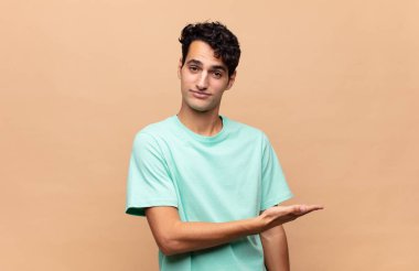 Genç yakışıklı adam neşeyle gülümsüyor, mutlu hissediyor ve fotokopi uzayında bir konsept gösteriyor.