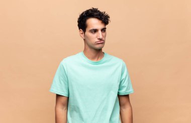 Genç, yakışıklı bir adam üzgün, üzgün ya da kızgın ve olumsuz bir tavırla, anlaşmazlık içinde somurtuyor.