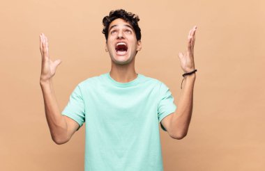 Genç yakışıklı adam kendini mutlu, şaşkın, şanslı ve şaşırmış hissediyor. Zaferi kutlarken iki elini de havaya kaldırıyor.