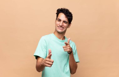 Genç yakışıklı adam kendini mutlu, havalı, tatmin olmuş, rahat ve başarılı hissediyor, kameraya bakıyor, seni seçiyor.