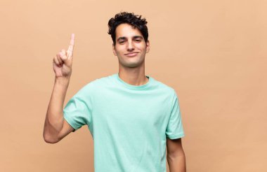 Genç yakışıklı adam neşeyle ve mutlulukla gülümsüyor, tek eliyle yukarıyı göstererek boşluğu kopyalıyor.