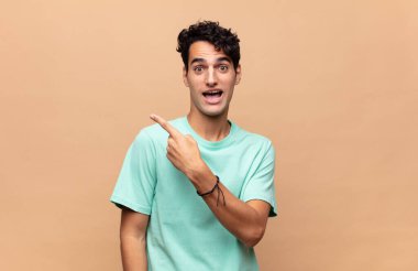 Genç ve yakışıklı bir adam heyecanlı ve şaşırmış görünüyor.