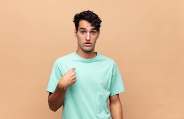 Genç yakışıklı adam mutlu, gururlu ve şaşırmış görünüyor, neşeli bir şekilde kendini gösteriyor, kendinden emin ve yüce hissediyor.