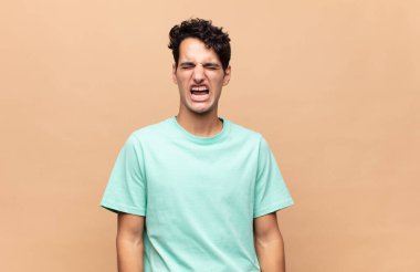 Genç yakışıklı adam agresif bir şekilde bağırıyor, çok kızgın, hayal kırıklığına uğramış, öfkeli ya da sinirli görünüyor, hayır