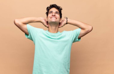 Genç yakışıklı adam gülümsüyor ve rahatlıyor, tatmin oluyor ve kaygısızca gülüyor.