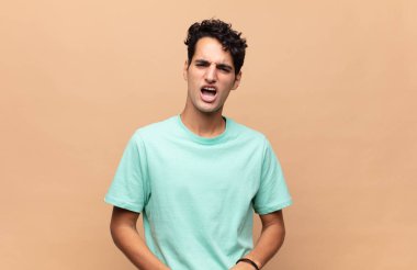 Şok olmuş, kızgın, sinirli ya da hayal kırıklığına uğramış, ağzı açık ve öfkeli genç bir adam.