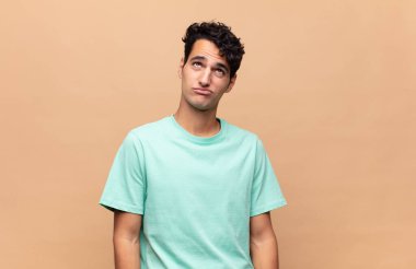 Genç ve yakışıklı adam kafası karışmış görünüyor, merak ediyor ya da bir sorunu çözmeye çalışıyor ya da düşünüyor.