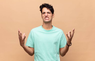 Genç yakışıklı adam öfkeyle bağırıyor, stresli hissediyor ve ellerini havaya kaldırıp neden ben diye bağırıyor.