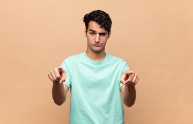 Genç ve yakışıklı bir adam kameraya hem parmaklarını hem de kızgın yüzünü göstererek sana görevini yapmanı söylüyor.