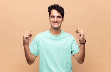 Genç yakışıklı adam mutlu, şaşırmış ve gururlu, bağırıyor ve başarıyı büyük bir gülümsemeyle kutluyor.