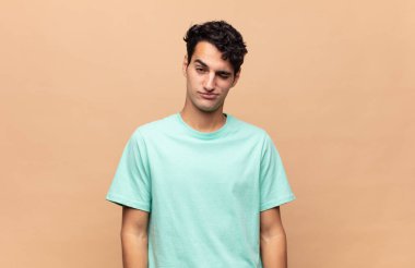 Genç yakışıklı adam mutlu ve arkadaş canlısı görünüyor, gülümsüyor ve sana olumlu bir tavırla göz kırpıyor.