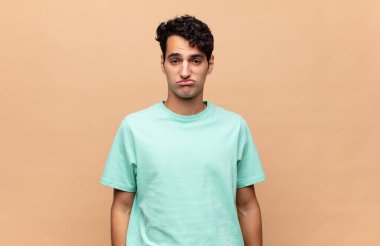 Genç yakışıklı adam üzgün ve mızmız, mutsuz bir bakışla, olumsuz ve hayal kırıklığına uğramış bir tavırla ağlıyor.