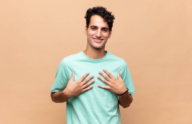 Genç yakışıklı adam mutlu görünüyor, şaşırmış, gururlu ve heyecanlı, kendini gösteriyor.