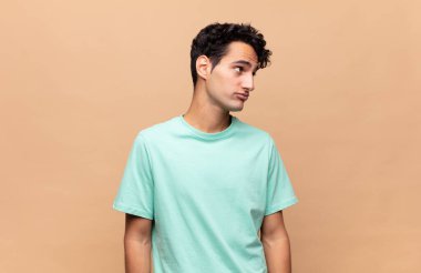 Genç yakışıklı adam merak ediyor, mutlu düşünceler ve fikirler düşünüyor, hayal kuruyor, kenarda yer arıyor.