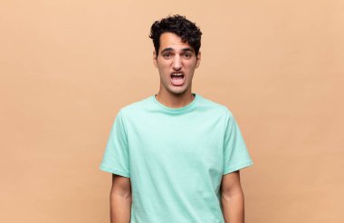 Genç yakışıklı adam korkmuş ve şok olmuş hissediyor, ağzı açık şaşkınlık içinde.