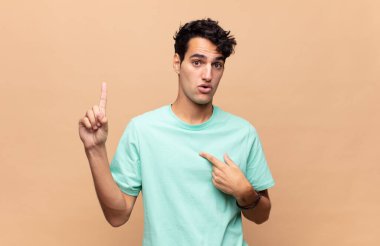 Genç yakışıklı adam gururlu ve şaşırmış, kendine güvenen, kendini bir numara gibi hisseden.