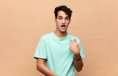 Şok olmuş ve ağzı açık, kendini işaret eden genç yakışıklı bir adam.