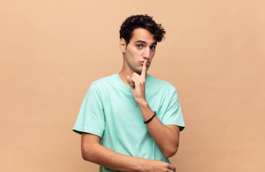 Genç yakışıklı adam sessizlik ve sessizlik istiyor, parmağıyla ağzının önünde işaret ediyor, 