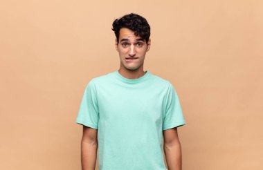 Şaşkın ve kafası karışmış genç bir adam gergin bir hareketle dudağını ısırıyor, sorunun cevabını bilmiyor.