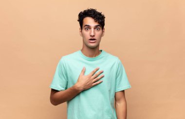 Genç yakışıklı adam şok olmuş ve şaşırmış hissediyor, gülümsüyor, el ele tutuşuyor, o olmaktan mutlu ya da minnettarlık gösteriyor.