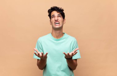 Genç yakışıklı adam umutsuz ve sinirli görünüyor, stresli, mutsuz ve sinirli, bağırıyor ve çığlık atıyor.