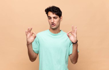 Genç yakışıklı adam şok olmuş, şaşırmış ve şaşırmış hissediyor. Onaylıyor. İki eliyle de onay işareti yapıyor.