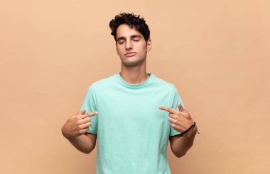 Genç yakışıklı adam gururlu, pozitif ve iki eliyle göğsünü gösteren