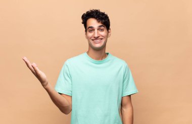 Genç yakışıklı adam kendini mutlu, şaşırmış ve neşeli hissediyor. Pozitif bir tavırla gülümsüyor. Bir çözüm ya da fikir buluyor.