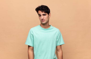 Genç yakışıklı adam şaşkın ve şaşkın hissediyor, aptal, afallamış bir ifadeyle beklenmedik bir şeye bakıyor.