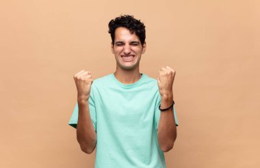 Genç yakışıklı adam zaferle bağırıyor, gülüyor, mutlu ve heyecanlı hissediyor başarıyı kutlarken.