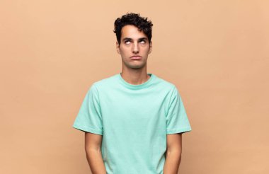 Genç ve yakışıklı adam şapşal ve komik görünüyor. Şaşı bakışlı, şakacı ve şakacı.