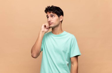 Yoğunlaşmış bakışları olan genç yakışıklı bir adam şüpheli bir ifadeyle yukarı ve yana bakıyor.