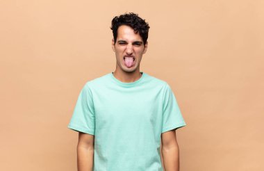 Genç yakışıklı adam tiksinmiş ve rahatsız olmuş hissediyor. Dilini dışarı çıkarıyor. İğrenç ve iğrenç bir şeyden hoşlanmıyor.