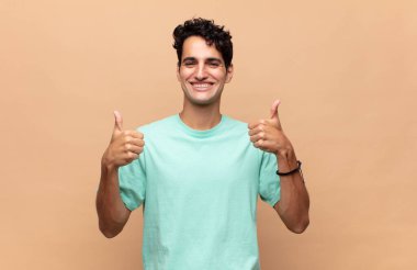 Genç yakışıklı adam gülümsüyor. Mutlu, pozitif, kendinden emin ve başarılı görünüyor.