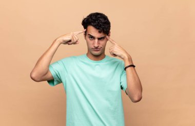 Ciddi ve konsantre görünümlü, beyin fırtınası yapan ve zorlu bir sorunu düşünen genç yakışıklı bir adam.