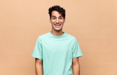 Genç yakışıklı adam mutlu ve hoş bir şekilde şaşırmış görünüyor. Büyülenmiş ve şok olmuş bir ifadeyle heyecanlanıyor.