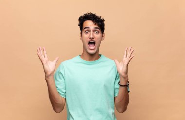 Genç ve yakışıklı bir adam beklenmedik bir sürpriz yüzünden şaşkın ve heyecanlı, güler yüzlü, şaşkın ve mutlu hissediyor.