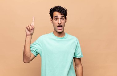 Genç yakışıklı bir adam bir fikri fark ettikten sonra mutlu ve heyecanlı bir dahi gibi hissediyor, neşeli bir şekilde parmağını kaldırıyor, eureka!